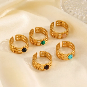 Set of five gold hollow sunburst rings with colorful inlaid gemstones on beige silk fabric