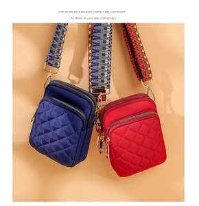 Detail of lightweight quilted nylon crossbody bags in navy blue and bright red colors