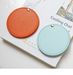 Detail of round PU leather mini pocket mirrors in orange and blue with lychee texture