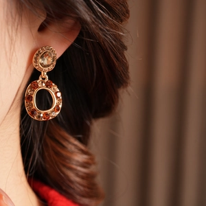 Macro detail of vintage hollow round earrings with amber crystals and olive gemstone