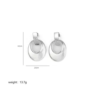 Macro detail of irregular silver geometric double-hoop earrings with mirror finish