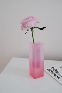 Detail of a frosted rectangular acrylic vase with pink gradient and a single rose