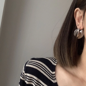 Close-up of tiered silver geometric drop earrings on model with layered metal disc design