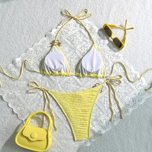 Flat lay of yellow ribbed bikini with metal chain straps and matching fashion accessories