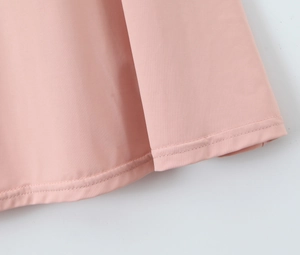 Gros plan de l'ourlet de robe rose avec double couture et texture de tissu lisse et douce