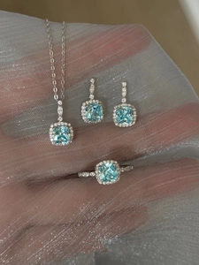 Detailed close-up of jewelry set with light blue square-cut stones on shimmering silver veil