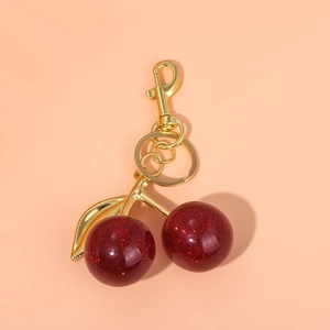 Detail of red glitter cherry keychain with gold metal leaves and secure lobster clasp