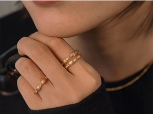 Detail of matte brushed gold S925 silver ring with small stones worn on finger