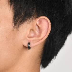Men's black stainless steel hoop earring with three grooves shown on person's ear