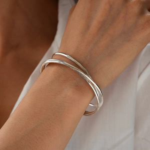Close-up of triple-layered silver geometric bangle styled with a white shirt
