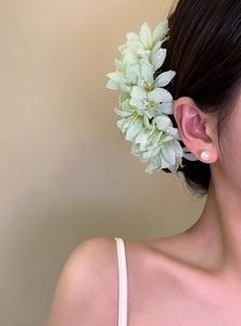 Detail view of an elegant light green fabric flower hair fork with dew drops worn by a model