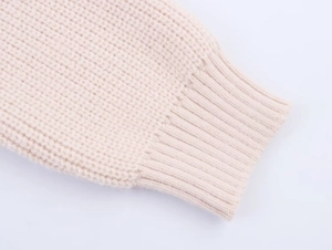 Detailed macro view of beige chunky knit sweater ribbed cuff highlighting soft texture