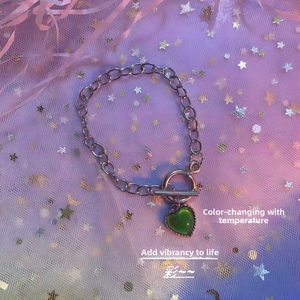 Close-up of temperature color-changing heart pendant on thick silver metal chain