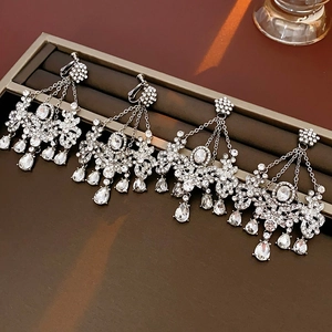 Macro view of silver fringe tassel earrings with rhinestones on dark leather tray