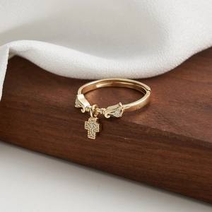 Detail of adjustable gold ring with sparkling cross pendant on soft fabric