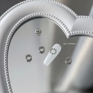 Détail de bijoux d'ongles couronne argent 9x13mm sur miroir coeur et faux ongle blanc
