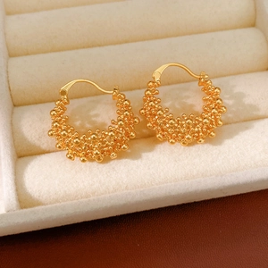 Vue macro de boucles d'oreilles créoles dorées avec texture de granulés métalliques fins