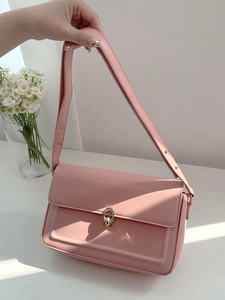 Detail of pink leather shoulder bag with gold clasp shown in natural sunlight