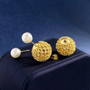 Elegant gold-hued hollow sphere earrings with crystals and white faux pearls on jewelry box