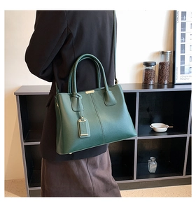 Dark green leather briefcase with gold hardware shown in a minimalist urban office setting