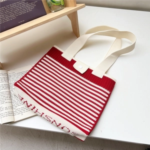 Detail of red and white striped knitted tote bag with beige handle and button closure