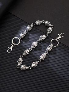 Detail of silver metallic skull chain links with spring hook and ring on black background