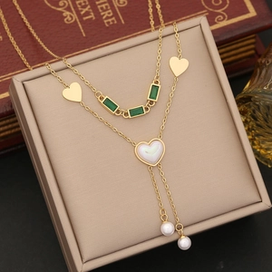 Double-layered gold necklace with green gems, pearls and heart charms in a beige gift box