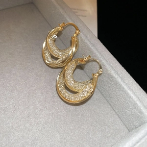 Detail of gold double-layered hoop earrings with crystal mesh texture and polished finish