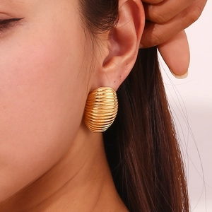 Close-up of golden striped dome stud earrings worn by a model for a chic look