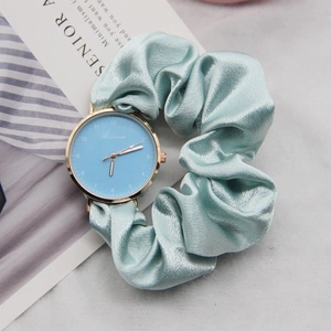 Detail of light blue ribbon scrunchie watch strap with golden dial and numbers
