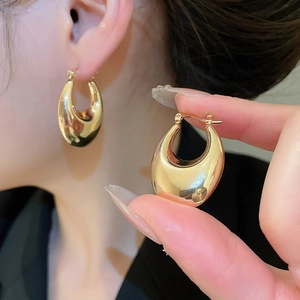 Detailed view of polished golden teardrop earrings with a smooth mirror finish