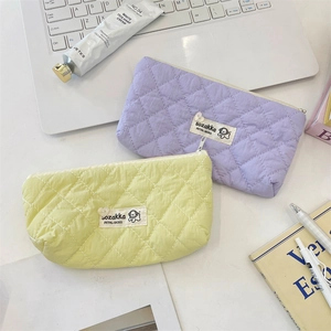 Close-up of quilted macaron stationery bags with dog label on a minimalist white desk