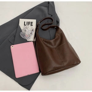 Detail view of dark brown faux leather tote with functional front pockets and grey blazer