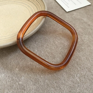 Macro detail van een vierkante amberkleurige hars armband met Franse vintage patronen