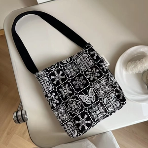 Detailed view of intricate white butterfly embroidery on a black canvas shoulder bag