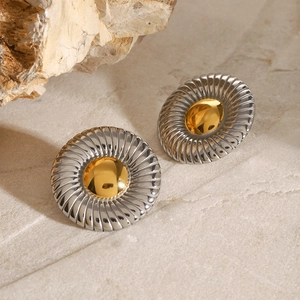 Close-up of twisted texture silver hoop earrings with gold hemispherical centers
