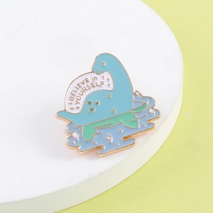 Detailed view of enamel dinosaur brooch with Believe in Yourself slogan and gold plating