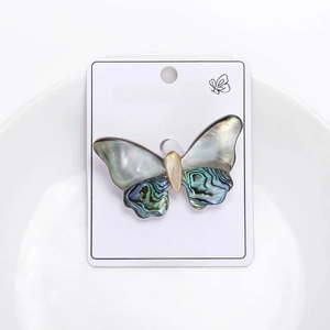 Detail of elegant shell butterfly brooch with iridescent green and blue wing textures