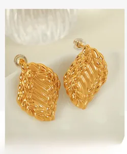Gros plan détaillé des boucles d'oreilles vintage dorées avec texture tissée torsadée