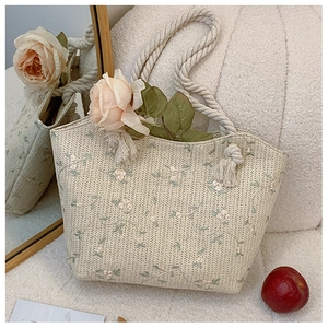 Détail du sac cabas en paille tressée avec broderie florale rose et anses en corde de chanvre