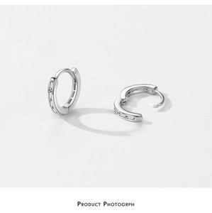 Macro detail of silver S925 huggie earrings with baguette-cut sparkling cubic zirconia