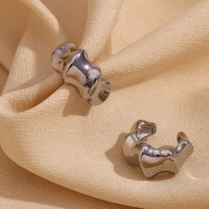 Macro view of 18K gold plated bamboo texture ear cuffs on a beige fabric background