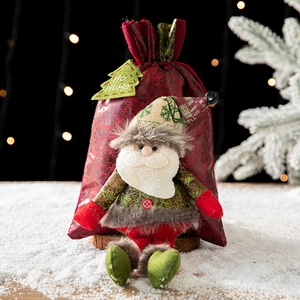Sac cadeau Père Noël en tissu rouge avec étiquette HO HO HO sur décor de neige