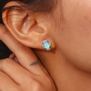 Detailed close-up of opal stud earring with zircon halo on ear for size reference