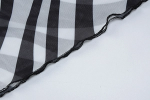 Detail of sheer black and white checkerboard mesh fabric with delicate lettuce trim edge
