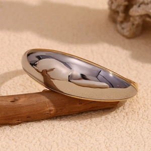 Macro detail of two-tone gold and silver stainless steel cuff bracelet on wood