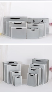 Detail of gray paper gift bags in various sizes with black handles and white borders