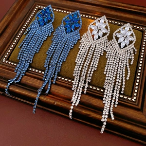 Macro detail of long silver tassel earrings with blue and white zircon rhinestones