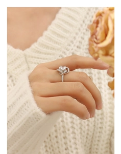 Détail d'une bague en argent sertie de zircon portée avec un pull blanc chic