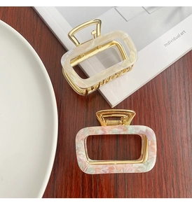 Detailed macro view of square hollow hair clips with marble texture and gold metal frame